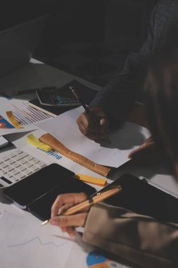 Tablet, akıllı telefon ve dizüstü bilgisayarlı iş belgeleri ve veri tartışan iki iş arkadaşı