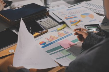 Tablet, akıllı telefon ve dizüstü bilgisayarlı iş belgeleri ve veri tartışan iki iş arkadaşı