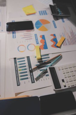 Tablet, akıllı telefon ve dizüstü bilgisayarlı iş belgeleri ve veri tartışan iki iş arkadaşı