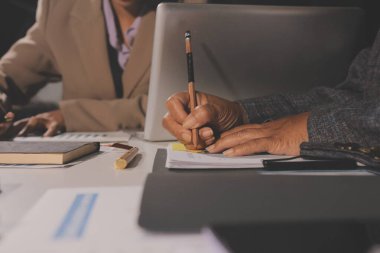 Tablet, akıllı telefon ve dizüstü bilgisayarlı iş belgeleri ve veri tartışan iki iş arkadaşı