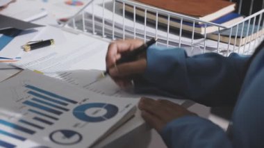 Yatırım sonuçlarını kontrol eden Asyalı erkek finans görevlisi veya muhasebeci, mali bütçe analizi sonuçları özetlemeyi ve denetim konsepti ve yatırım sonuçlarını toplantıya rapor etmeyi planlıyor.