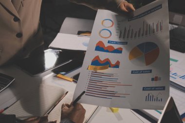 Tablet, akıllı telefon ve dizüstü bilgisayarlı iş belgeleri ve veri tartışan iki iş arkadaşı