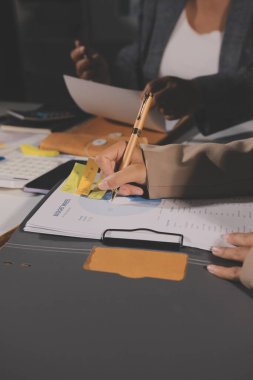 Tablet, akıllı telefon ve dizüstü bilgisayarlı iş belgeleri ve veri tartışan iki iş arkadaşı