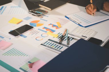 Tablet, akıllı telefon ve dizüstü bilgisayarlı iş belgeleri ve veri tartışan iki iş arkadaşı