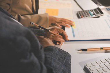 Tablet, akıllı telefon ve dizüstü bilgisayarlı iş belgeleri ve veri tartışan iki iş arkadaşı