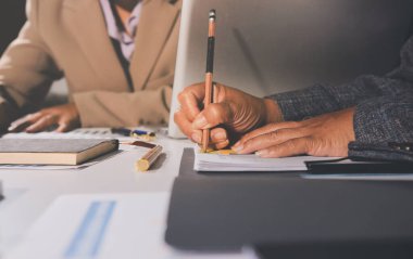 Tablet, akıllı telefon ve dizüstü bilgisayarlı iş belgeleri ve veri tartışan iki iş arkadaşı