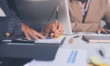 Tablet, akıllı telefon ve dizüstü bilgisayarlı iş belgeleri ve veri tartışan iki iş arkadaşı