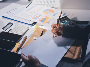 Tablet, akıllı telefon ve dizüstü bilgisayarlı iş belgeleri ve veri tartışan iki iş arkadaşı