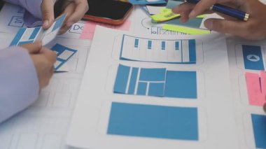 Uxui tasarımcılarından oluşan bir ekip bilgisayar ekranını işaret ederek ofiste yeni mobil uygulama tasarımını tartışıyor.