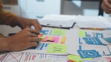 Uxui tasarımcılarından oluşan bir ekip bilgisayar ekranını işaret ederek ofiste yeni mobil uygulama tasarımını tartışıyor.