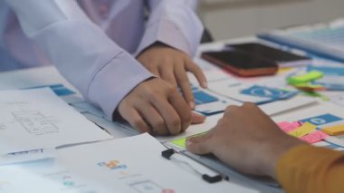 Uxui tasarımcılarından oluşan bir ekip bilgisayar ekranını işaret ederek ofiste yeni mobil uygulama tasarımını tartışıyor.