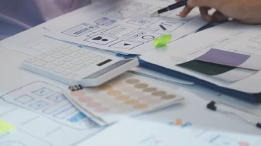 Uxui tasarımcılarından oluşan bir ekip bilgisayar ekranını işaret ederek ofiste yeni mobil uygulama tasarımını tartışıyor.