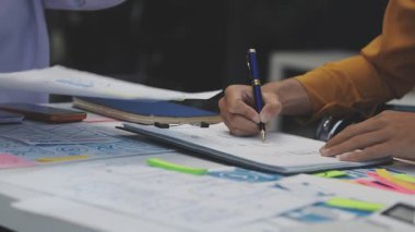 Uxui tasarımcılarından oluşan bir ekip bilgisayar ekranını işaret ederek ofiste yeni mobil uygulama tasarımını tartışıyor.