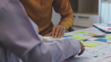 Uxui tasarımcılarından oluşan bir ekip bilgisayar ekranını işaret ederek ofiste yeni mobil uygulama tasarımını tartışıyor.