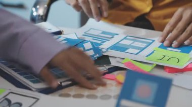 Uxui tasarımcılarından oluşan bir ekip bilgisayar ekranını işaret ederek ofiste yeni mobil uygulama tasarımını tartışıyor.