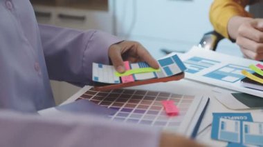 Uxui tasarımcılarından oluşan bir ekip bilgisayar ekranını işaret ederek ofiste yeni mobil uygulama tasarımını tartışıyor.