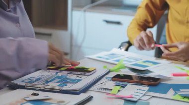 Uxui tasarımcılarından oluşan bir ekip bilgisayar ekranını işaret ederek ofiste yeni mobil uygulama tasarımını tartışıyor.