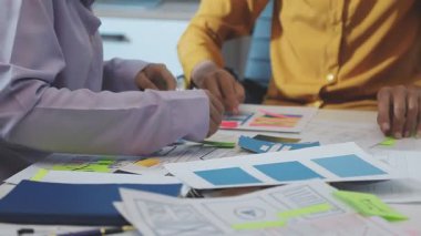 Uxui tasarımcılarından oluşan bir ekip bilgisayar ekranını işaret ederek ofiste yeni mobil uygulama tasarımını tartışıyor.