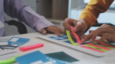 Uxui tasarımcılarından oluşan bir ekip bilgisayar ekranını işaret ederek ofiste yeni mobil uygulama tasarımını tartışıyor.