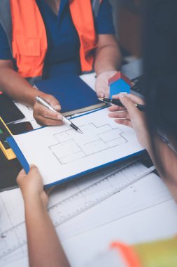 Mühendis ve mimar, hareketli bir şantiyede planlar ve inşaat planlarını birlikte gözden geçiriyorlar.