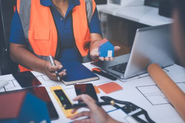 Mühendis ve mimar, hareketli bir şantiyede planlar ve inşaat planlarını birlikte gözden geçiriyorlar.