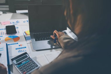 Tablet, akıllı telefon ve dizüstü bilgisayarlı iş belgeleri ve veri tartışan iki iş arkadaşı