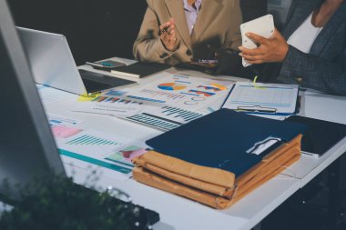 Tablet, akıllı telefon ve dizüstü bilgisayarlı iş belgeleri ve veri tartışan iki iş arkadaşı