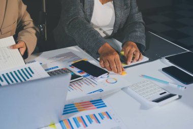 Tablet, akıllı telefon ve dizüstü bilgisayarlı iş belgeleri ve veri tartışan iki iş arkadaşı