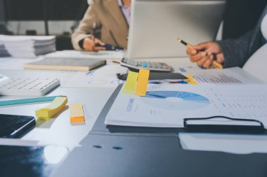 Tablet, akıllı telefon ve dizüstü bilgisayarlı iş belgeleri ve veri tartışan iki iş arkadaşı