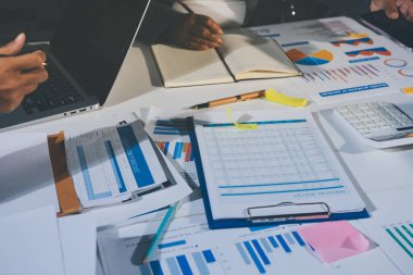 Tablet, akıllı telefon ve dizüstü bilgisayarlı iş belgeleri ve veri tartışan iki iş arkadaşı