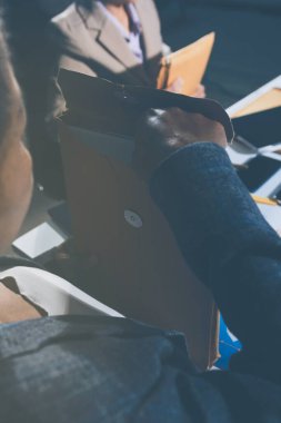 Tablet, akıllı telefon ve dizüstü bilgisayarlı iş belgeleri ve veri tartışan iki iş arkadaşı