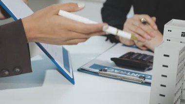 Professional accountants working in a well lit office, analyzing financial data and reviewing statements with a calculator and pen. Audit and taxes theme in business