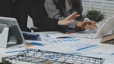 Professional accountants working in a well lit office, analyzing financial data and reviewing statements with a calculator and pen. Audit and taxes theme in business