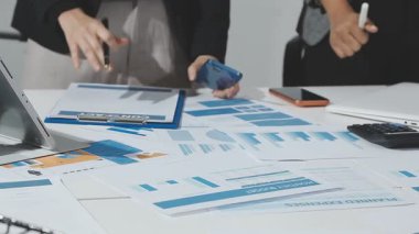 Professional accountants working in a well lit office, analyzing financial data and reviewing statements with a calculator and pen. Audit and taxes theme in business