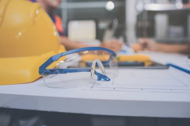 Mühendis ve mimar, hareketli bir şantiyede planlar ve inşaat planlarını birlikte gözden geçiriyorlar.