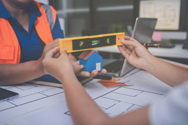 Mühendis ve mimar, hareketli bir şantiyede planlar ve inşaat planlarını birlikte gözden geçiriyorlar.