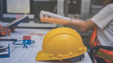 Mühendis ve mimar, hareketli bir şantiyede planlar ve inşaat planlarını birlikte gözden geçiriyorlar.