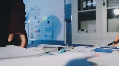 Bir grup menajer iş saatinden sonra akşam saatlerinde takım toplantısı yapıyor. Meslektaşlar Yıllık Finansal ve Pazarlama Raporlarını Tartışıyor. Yaratıcı Ofis 'te takım çalışması. Eller Üzerinde Kapat.