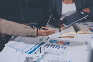 Tablet, akıllı telefon ve dizüstü bilgisayarlı iş belgeleri ve veri tartışan iki iş arkadaşı