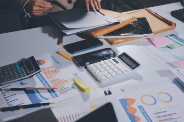 Tablet, akıllı telefon ve dizüstü bilgisayarlı iş belgeleri ve veri tartışan iki iş arkadaşı