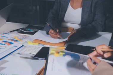 Tablet, akıllı telefon ve dizüstü bilgisayarlı iş belgeleri ve veri tartışan iki iş arkadaşı