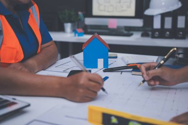 Mühendis ve mimar, hareketli bir şantiyede planlar ve inşaat planlarını birlikte gözden geçiriyorlar.