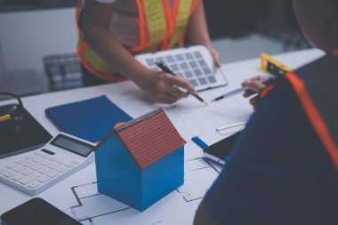 Mühendis ve mimar, hareketli bir şantiyede planlar ve inşaat planlarını birlikte gözden geçiriyorlar.