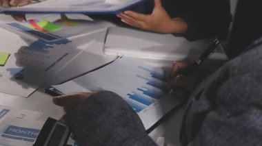 Modern ofis, iş ve teknoloji konseptinde iş adamlarının ellerinin kalemini tutup grafik çizelgesiyle çalışmak.