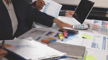 İş ekibi finansal belgeler ve dizüstü bilgisayarla çalışıyor.