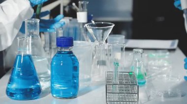 Laboratuvar asistanı elinde kimyasal cam tüplerle test tüpü tutuyor..