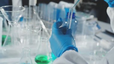 Laboratuvarda elinde sıvı olan bir deney tüpü tutan bilim adamı.