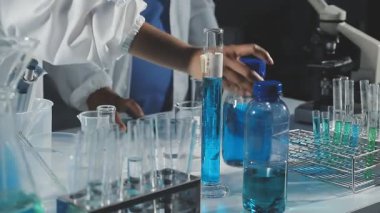 Laboratuvarda deney tüpleri ve kimyasal sıvıyla koruyucu kıyafet giyen bilim adamı.