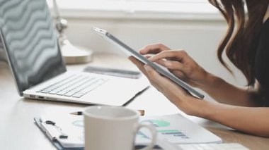 Kadın evde dizüstü bilgisayar ve cep telefonuyla çalışıyor.