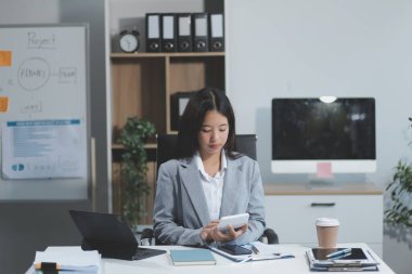 Asyalı iş kadını dizüstü bilgisayar kullanıyor ve ofiste hesap makinesi ile çalışıyor, mali raporu, iş planı yatırımını, mali analiz konseptini analiz etmeyi planlıyor..